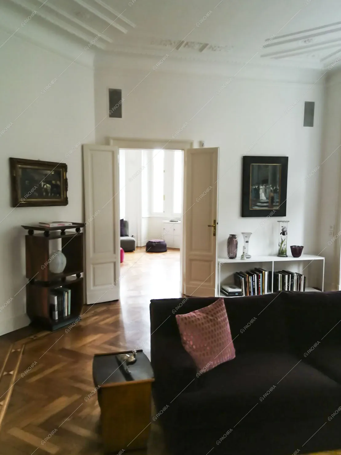 Soggiorno con divano viola, pareti bianche, soffitto con boiserie e pavimento in parquet a spina di pesce