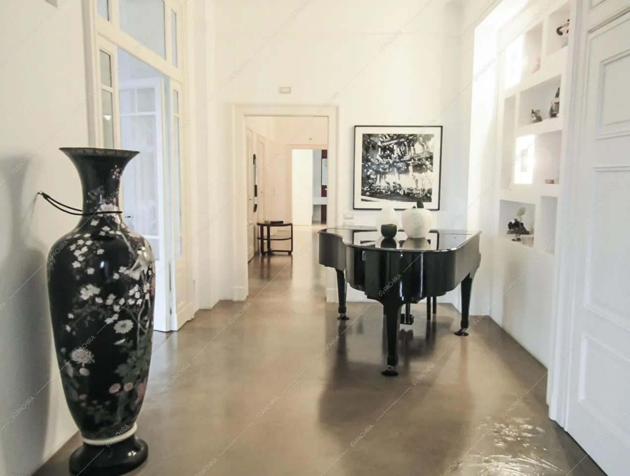 Pavimento grigio in resina in corridoio dalle pareti bianche con pianoforte