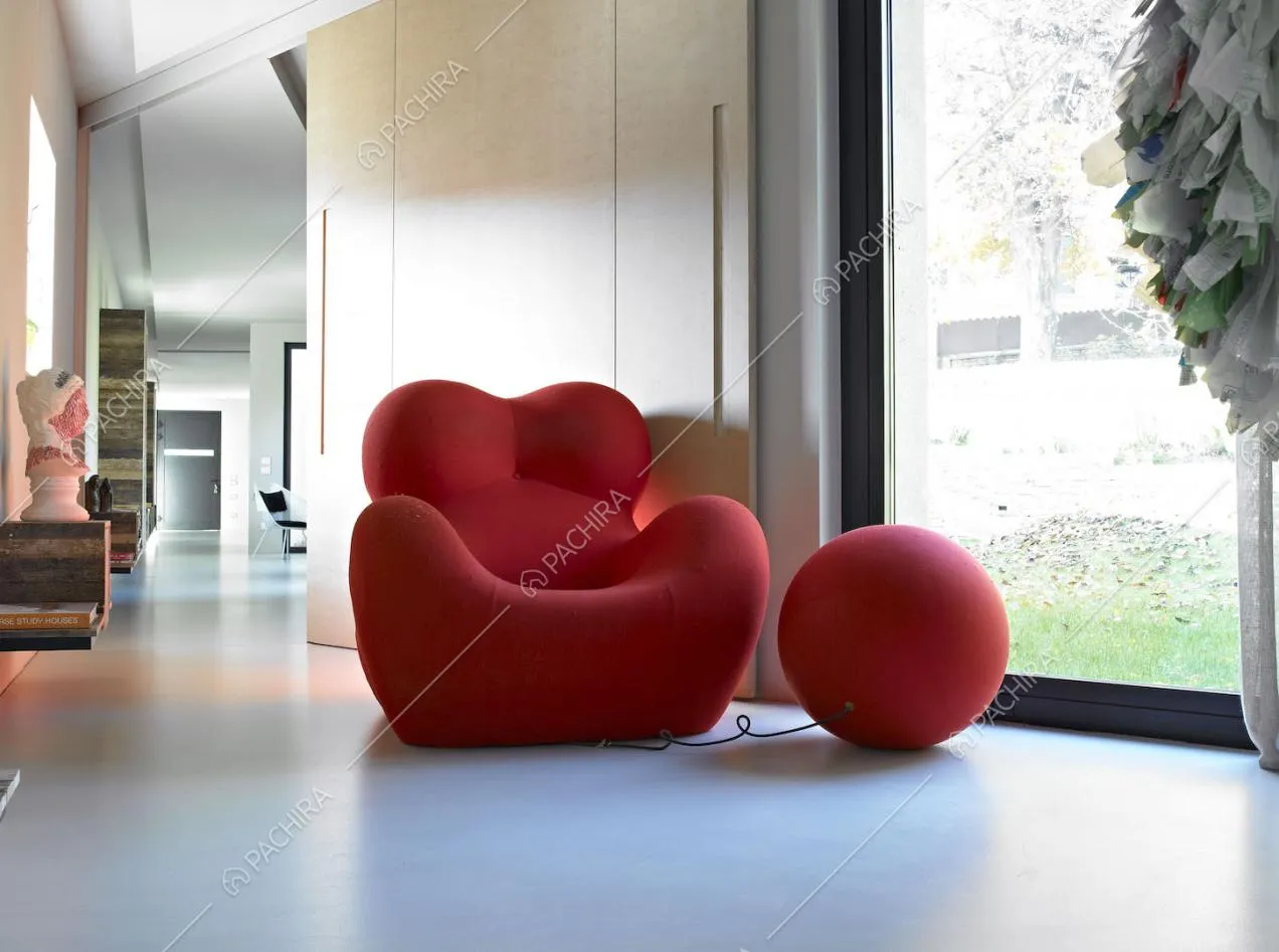 Poltrona rossa di design con poggiapiedi e vetrata