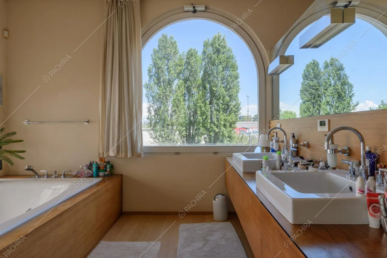 Luminoso bagno con vasca, doppio lavandino e pavimento in parquet