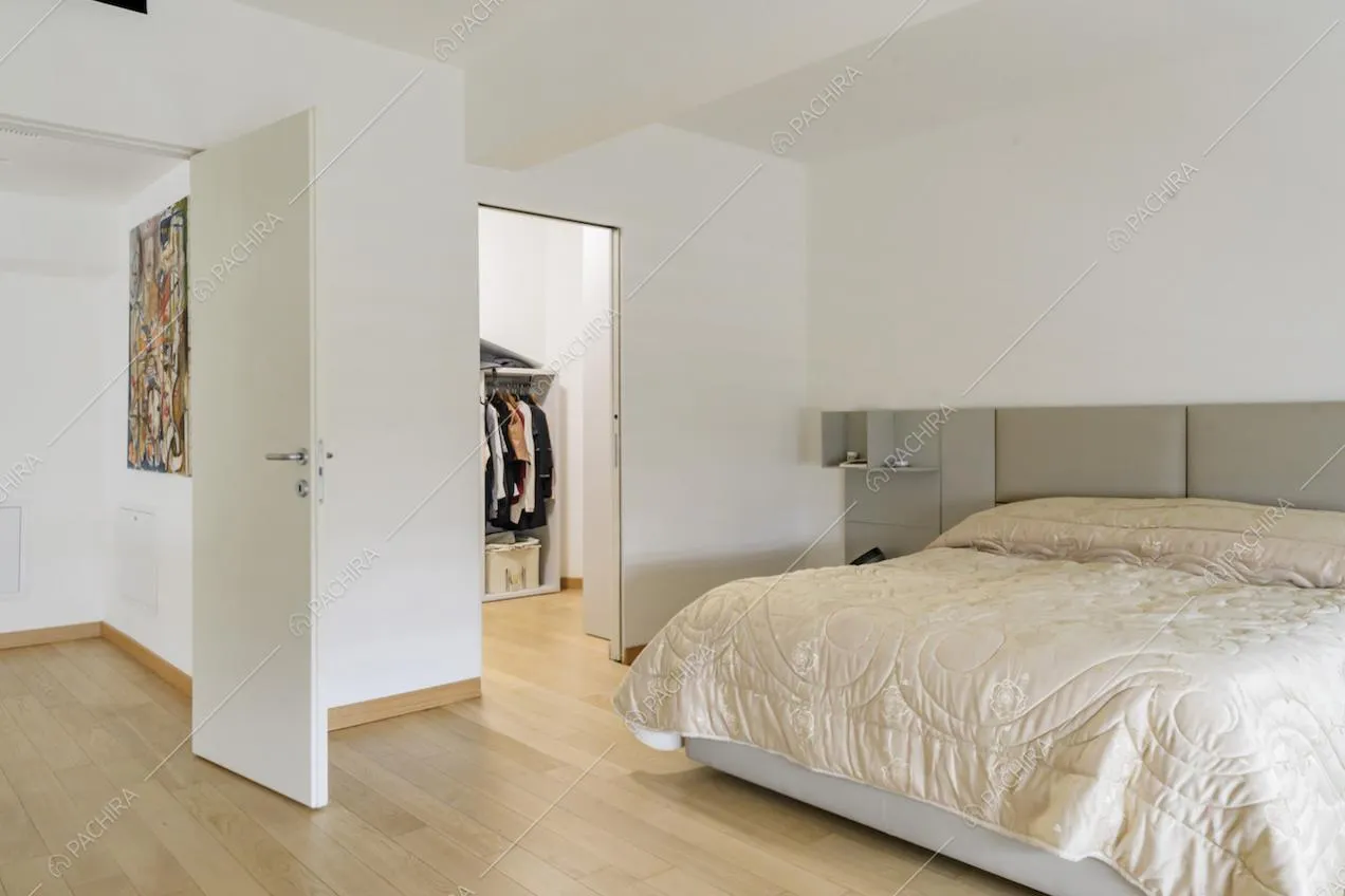 Camera da letto minimal con pavimento in parquet, pareti bianche e cabina armadio