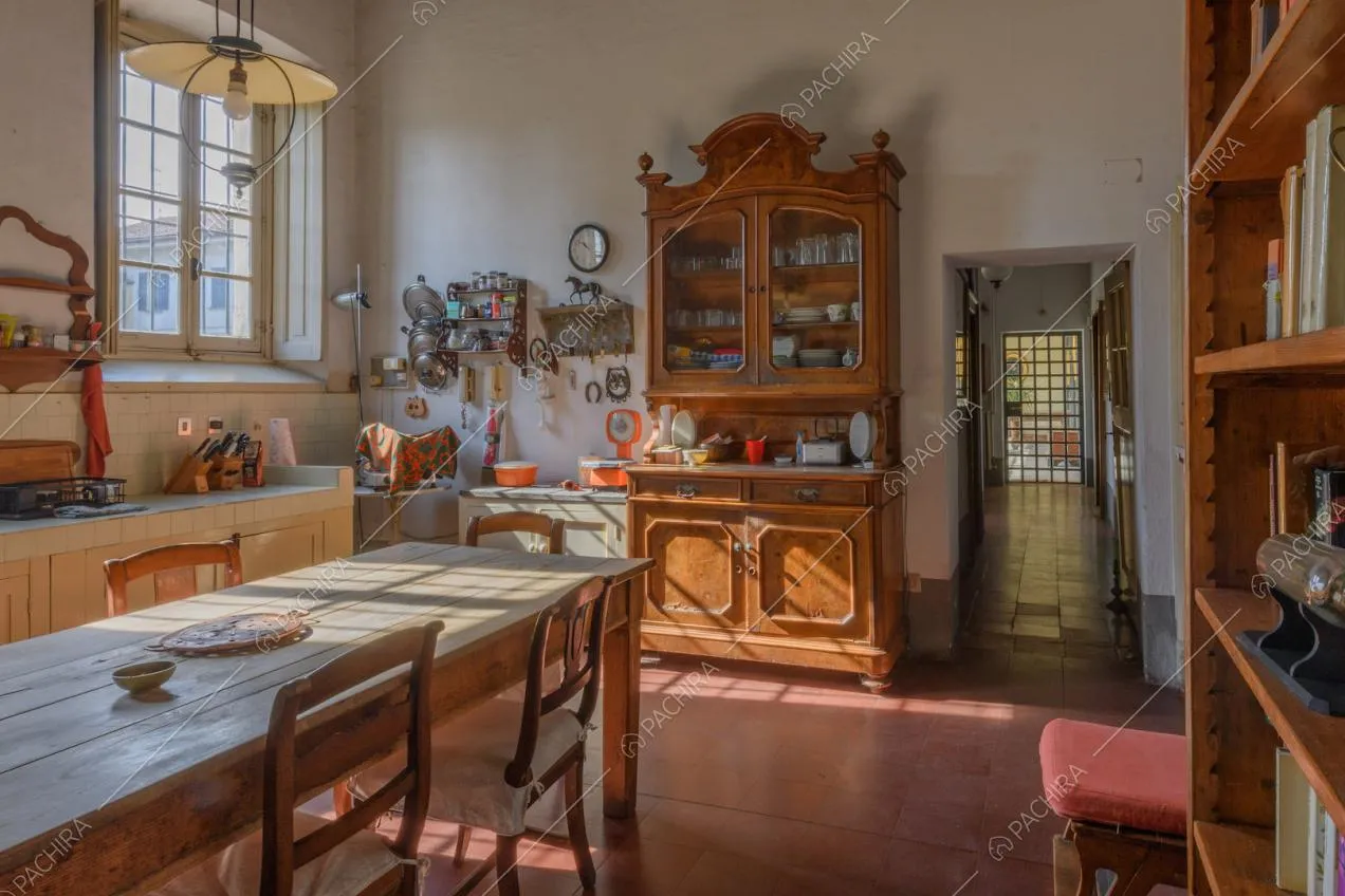 Cucina con pavimento in piastrelle rosse, credenza in legno con boiserie e vista sulla porta d'ingresso