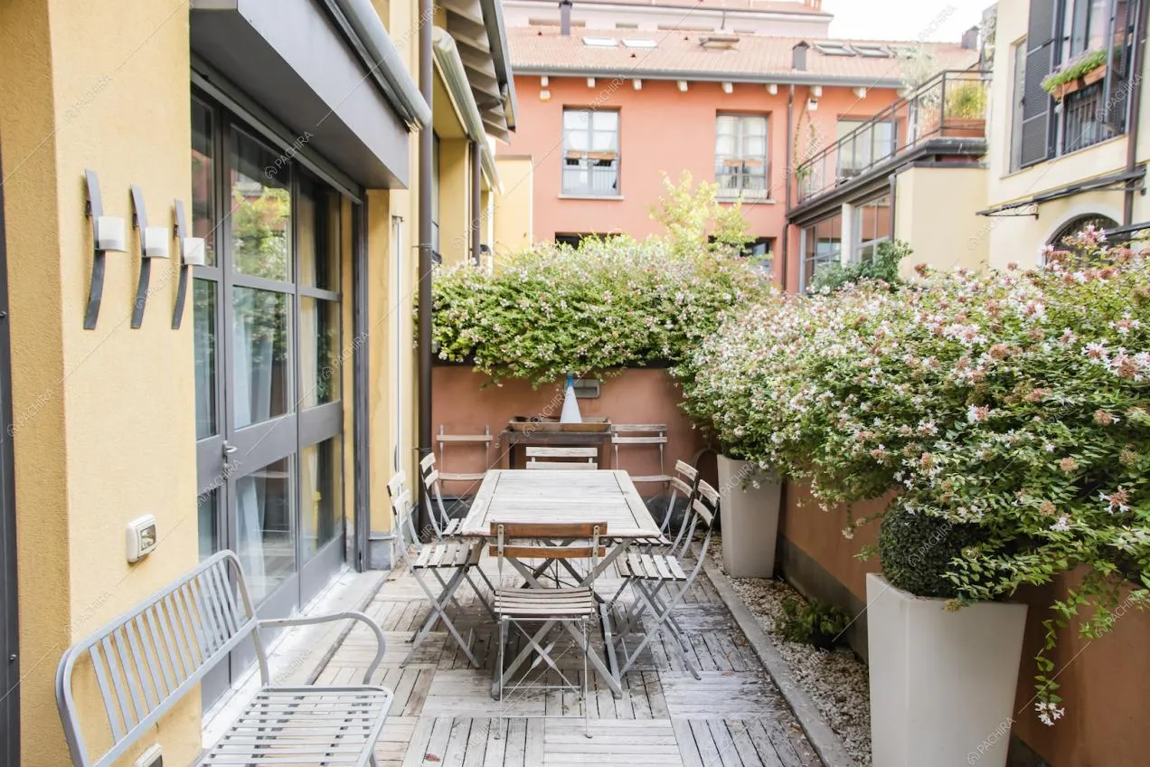 Terrazza con tavolo da pranzo da esterni, pavimento in parquet e porta-finestra in stile industriale