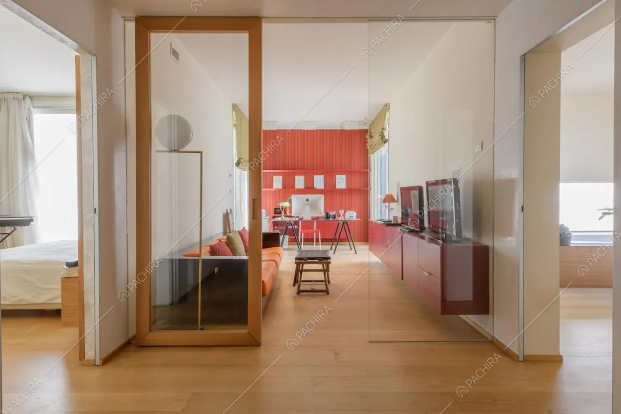 Studio con divano, scrivania, porte a vetri e pavimento in parquet