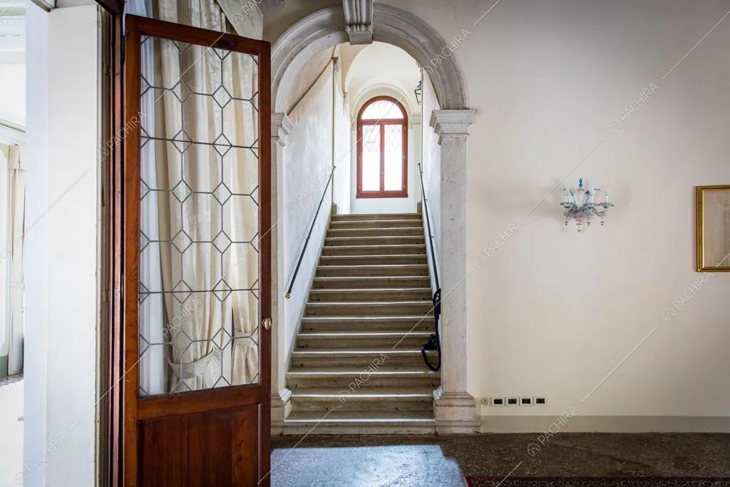 Atrio con porta a vetro in legno e vista sulle scale