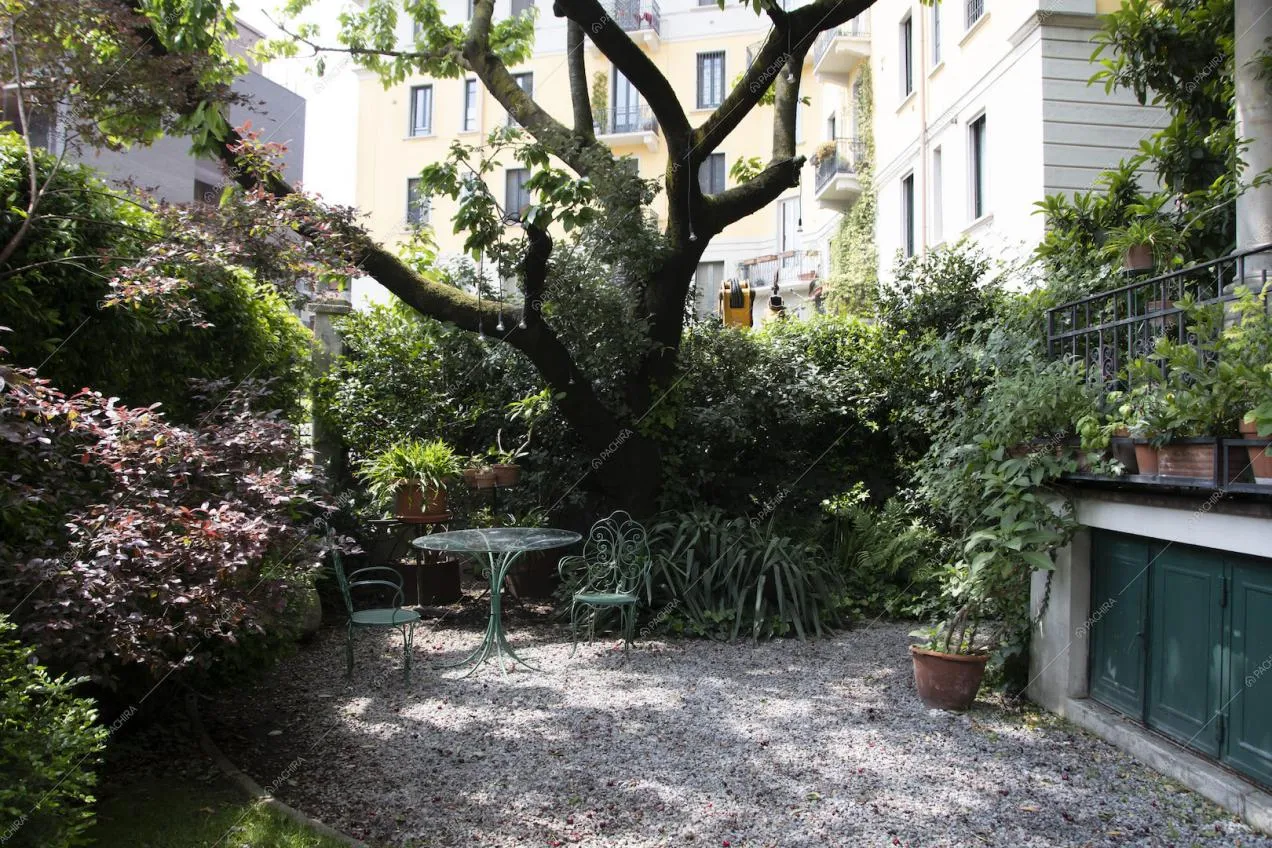 Giardino con pavimentazione in ciottoli e tavolo e sedie verdi da esterni