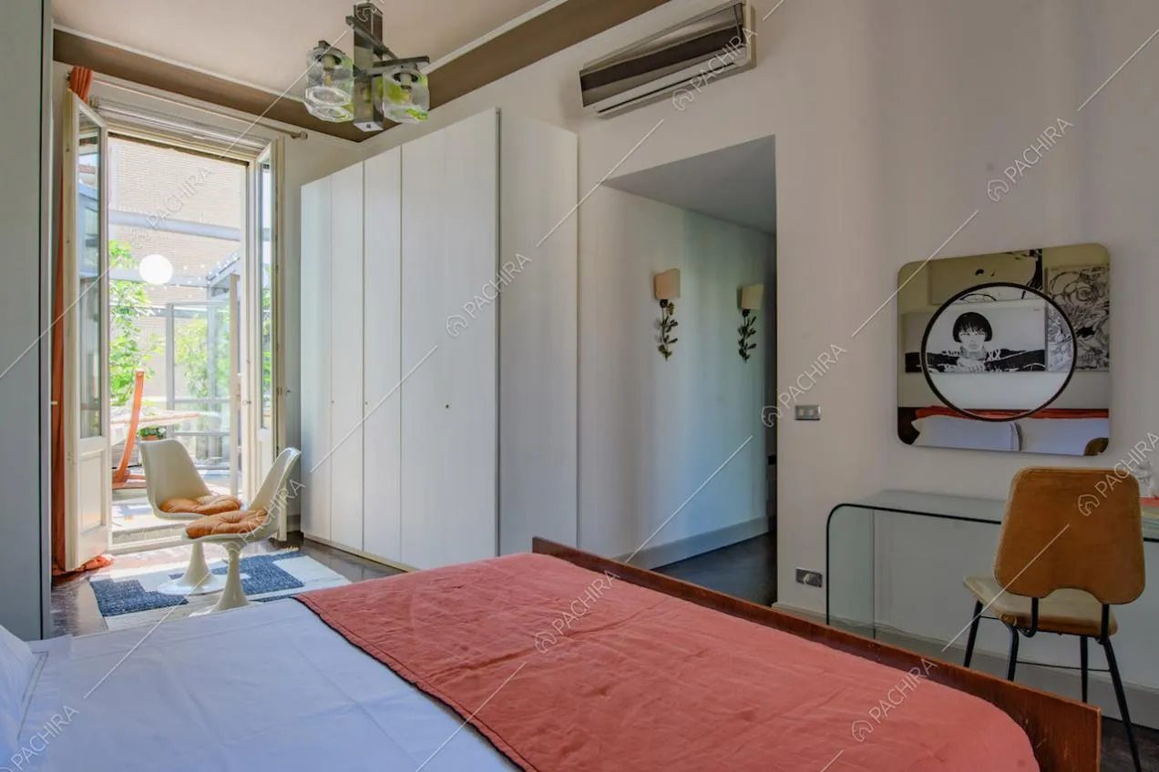Luminosa camera da letto matrimoniale con pareti bianche e porta-finestra