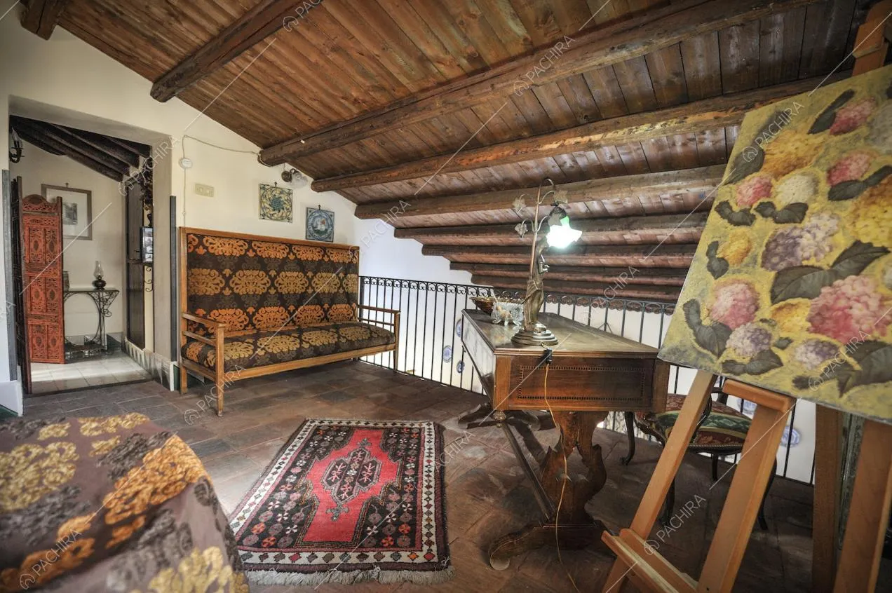 Antica scrivania in legno, tappeto, cavalletto da pittura e sottotetto con travi a vista