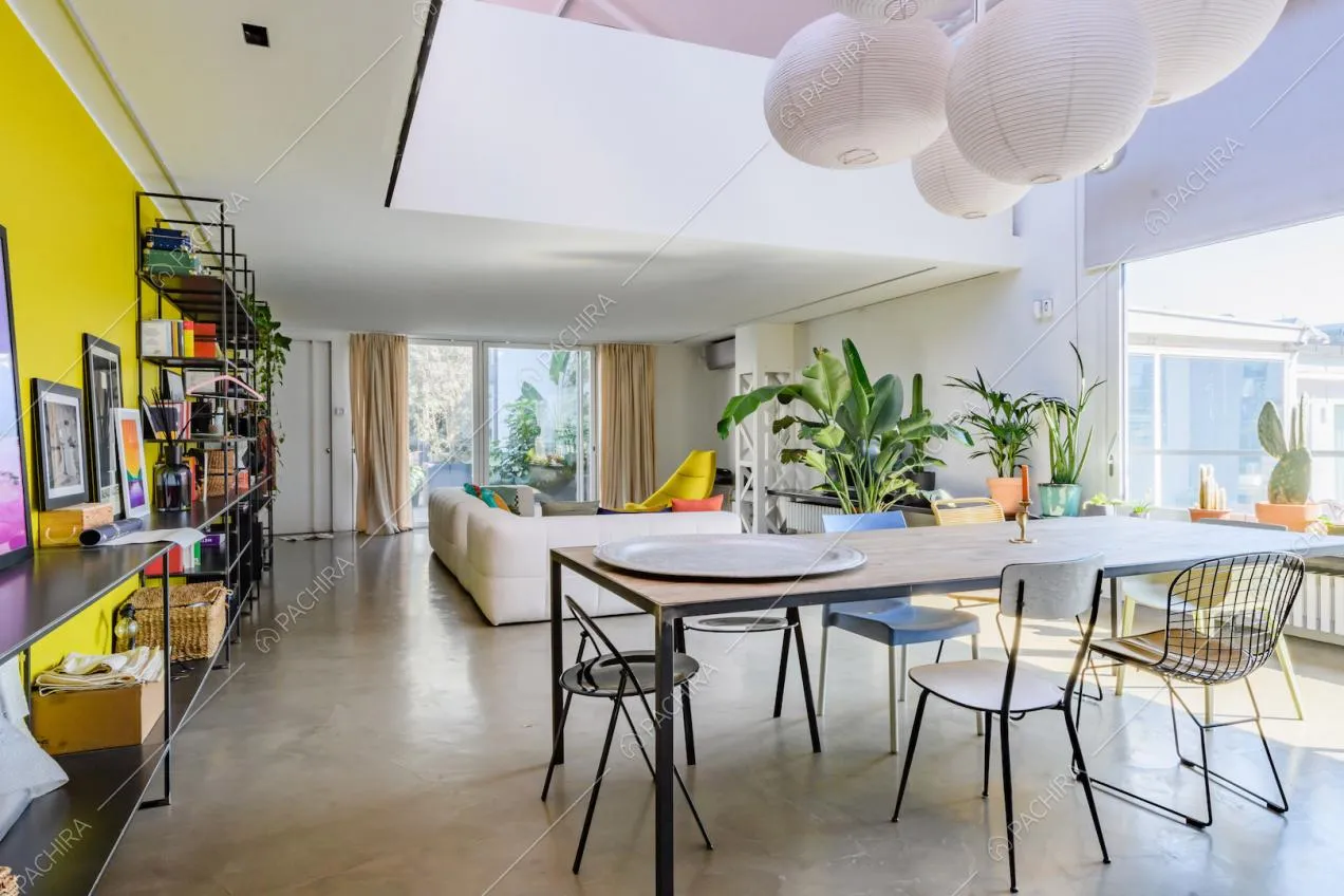 Tavolo da pranzo nella luminosa zona living con vetrate, parete gialla e vista sul parapetto del soppalco