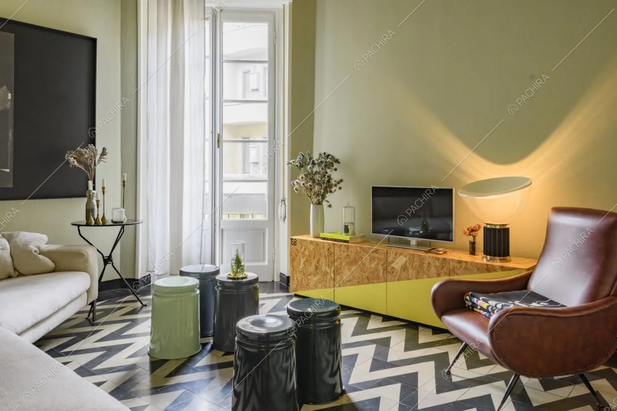 Salotto moderno con poltrona in pelle, televisore e tavolini colorati
