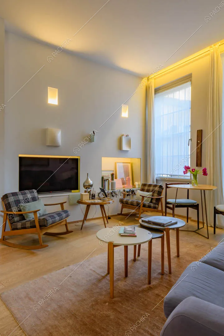 Luminoso salotto con pavimento in parquet, sedie a dondolo e divano blu