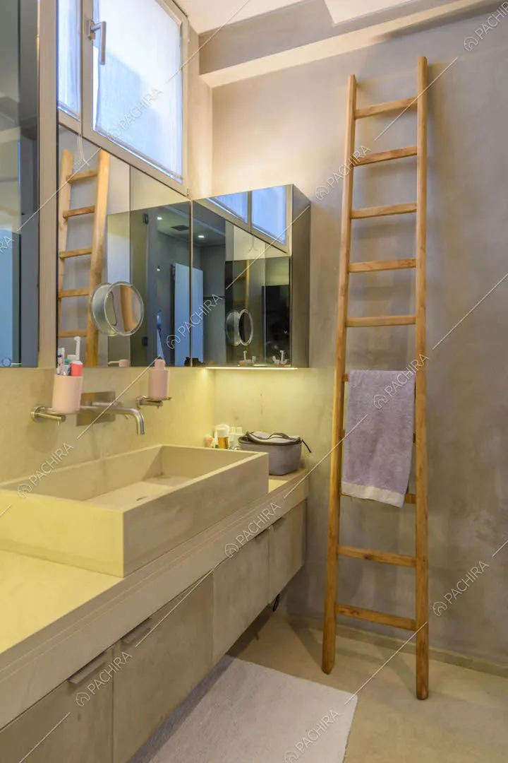 Luminoso bagno con mobile sospeso, pavimento in cemento e scala a pioli in legno grezzo
