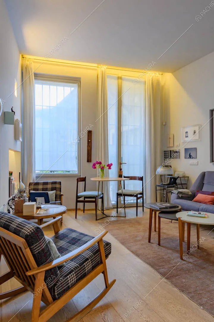 Salotto con sedia a dondolo, divani, pavimento in parquet e porta-finestra
