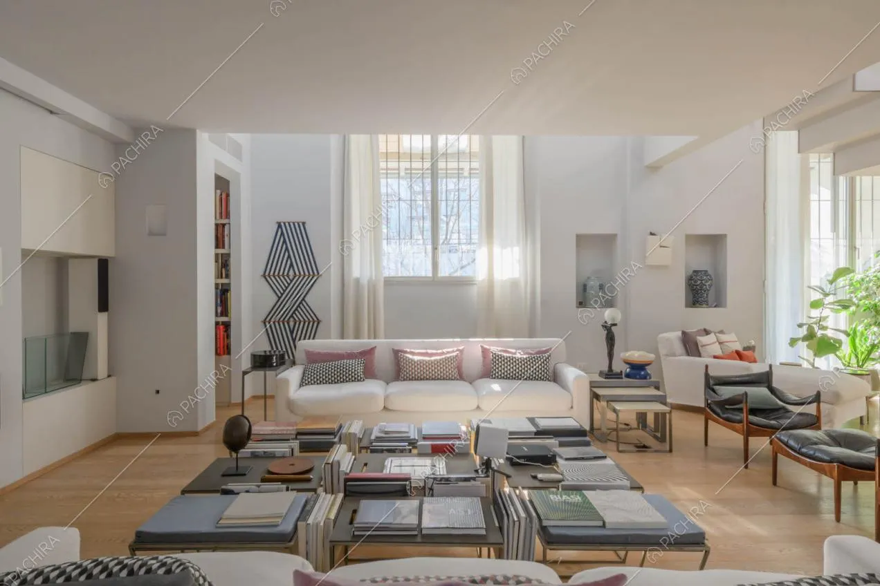 Spazioso salotto con doppio divano bianco, camino e pavimento in parquet