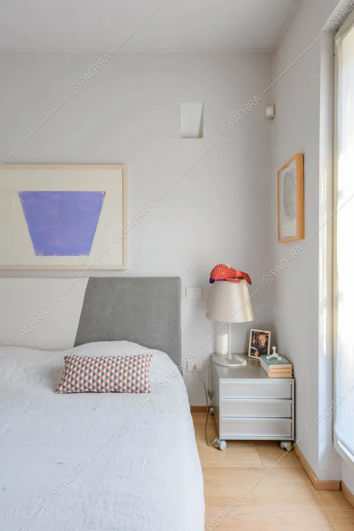Camera da letto matrimoniale con grande finestra e pavimento in parquet