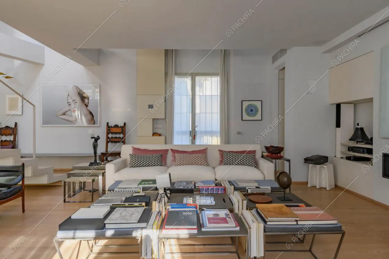 Tavolino di design nel salotto con divani bianchi, camino e pavimento in parquet