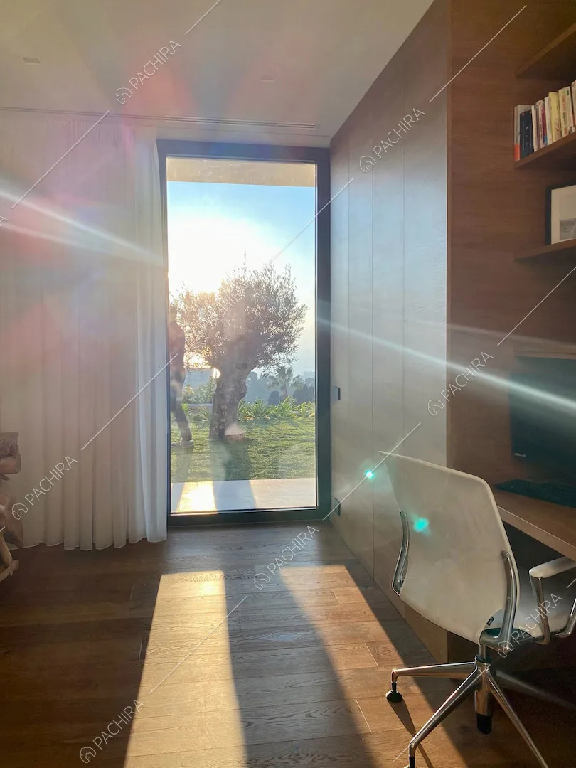 Studio con scrivania, pavimento in parquet, armadio a muro e vetrata con vista sul giardino