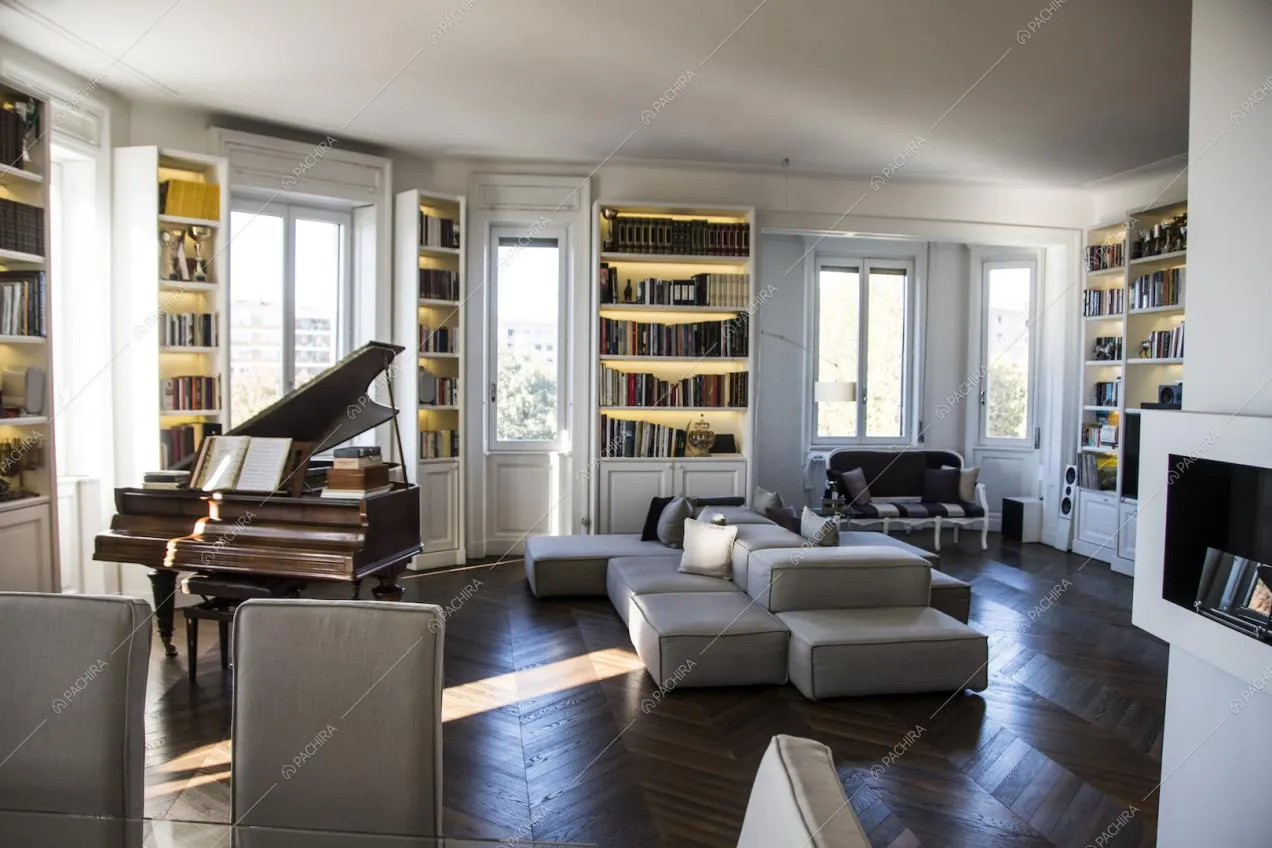 Librerie e pianoforte nel living di questo luminoso appartamento a Milano