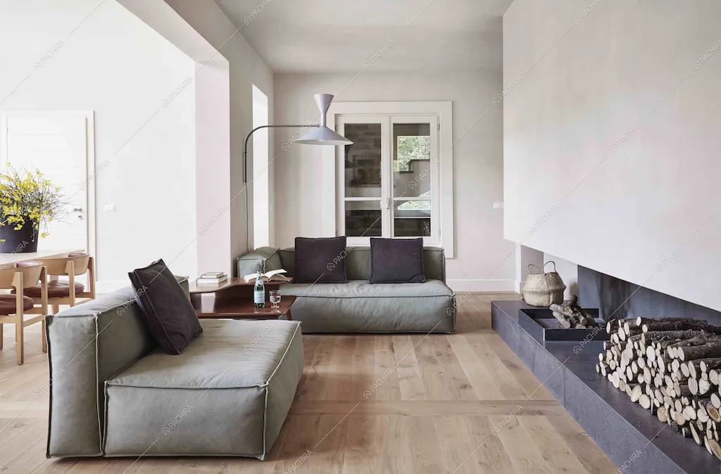 Il living della Location Rovere: divani grigi, camino e pavimento in parquet