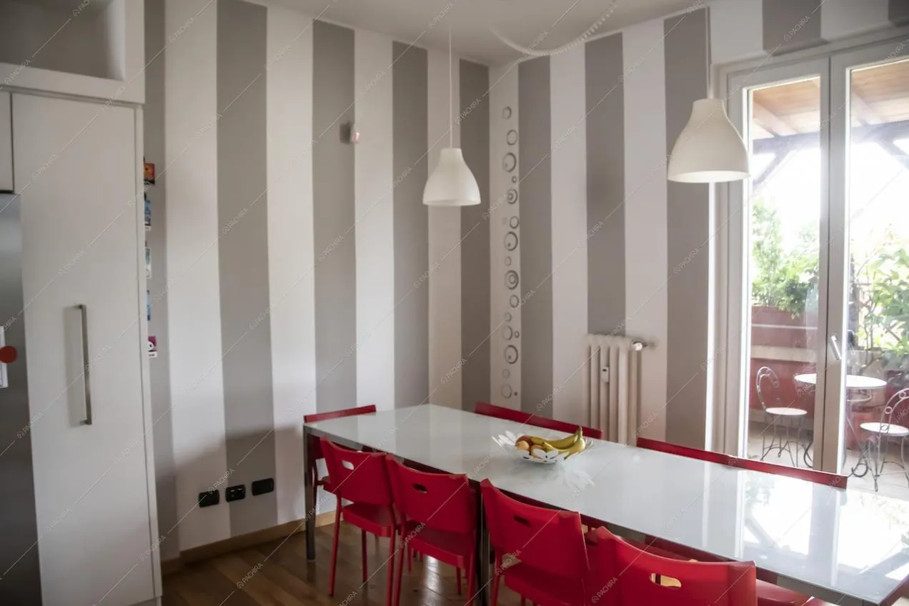 Sedie rosse e pareti decorate a strisce per la sala da pranzo della Location Vanda