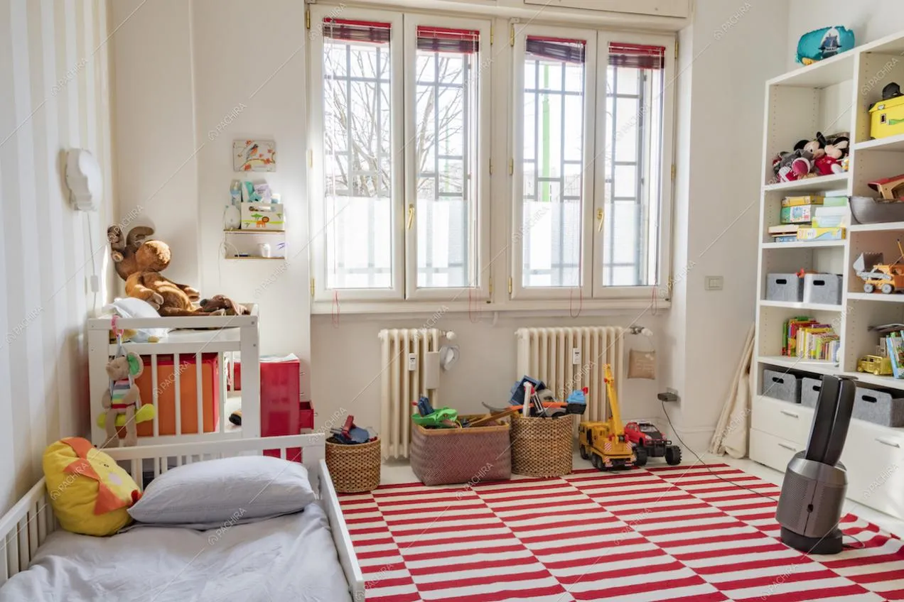 Tappeto a strisce rosse e giochi nella camera dei bambini