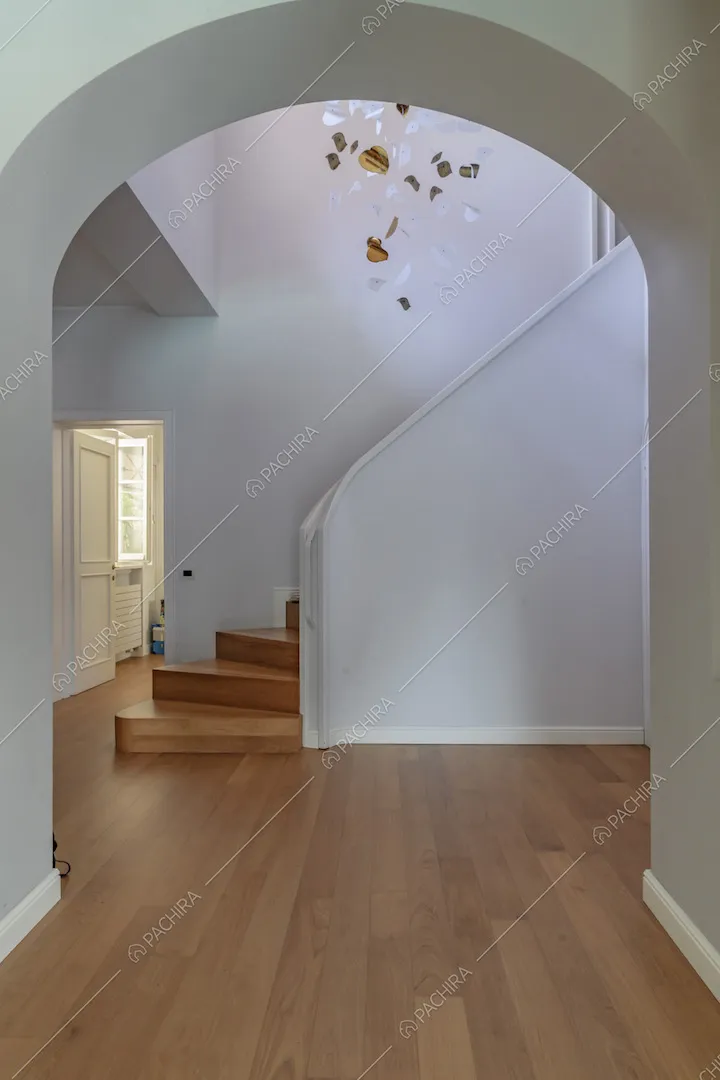 Atrio con pavimento in parquet, arco a volta, scale e pareti bianche