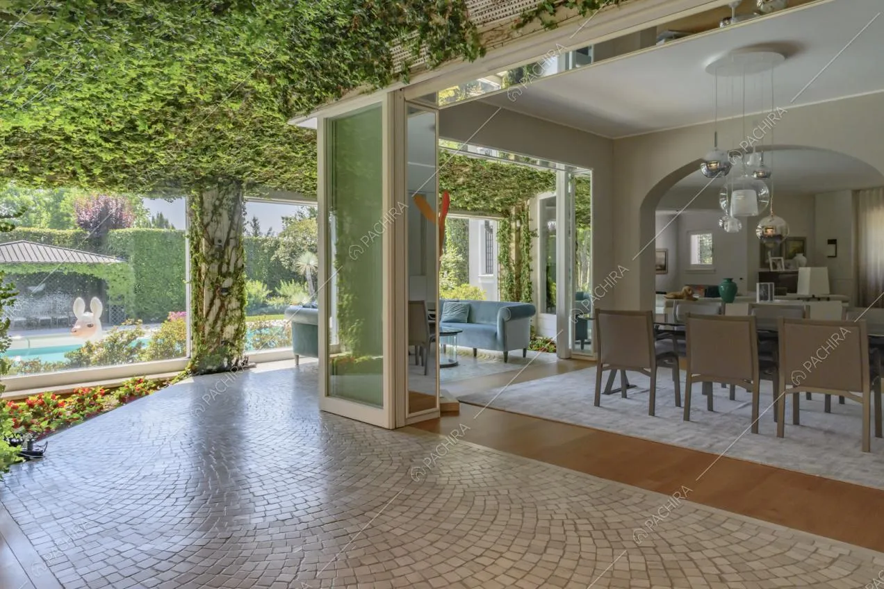 Veranda con rampicanti sul soffitto, pavimento in piastrelle e vista sulla sala da pranzo