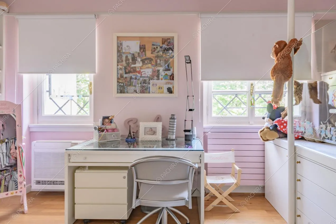 Scrivania nella camera dei bambini con pavimento in parquet, pareti rosa e letto rialzato