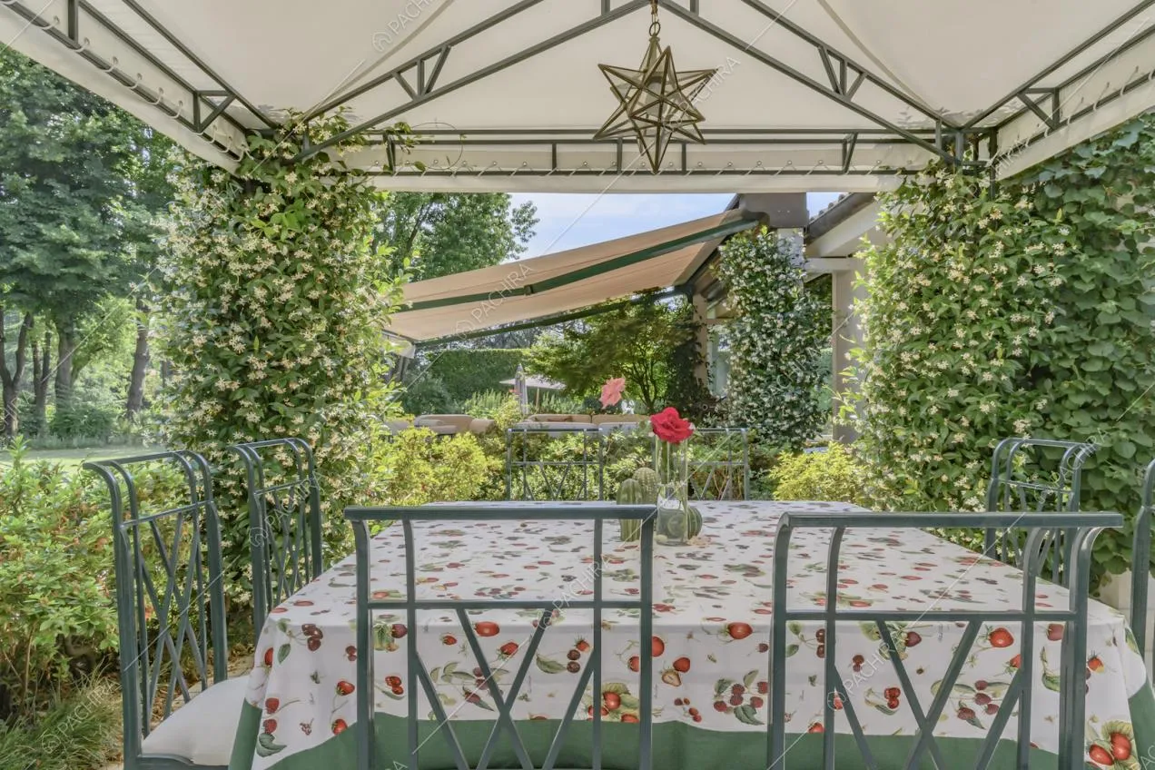 Nel gazebo immerso nel verde tavolo da pranzo con sedie in metallo