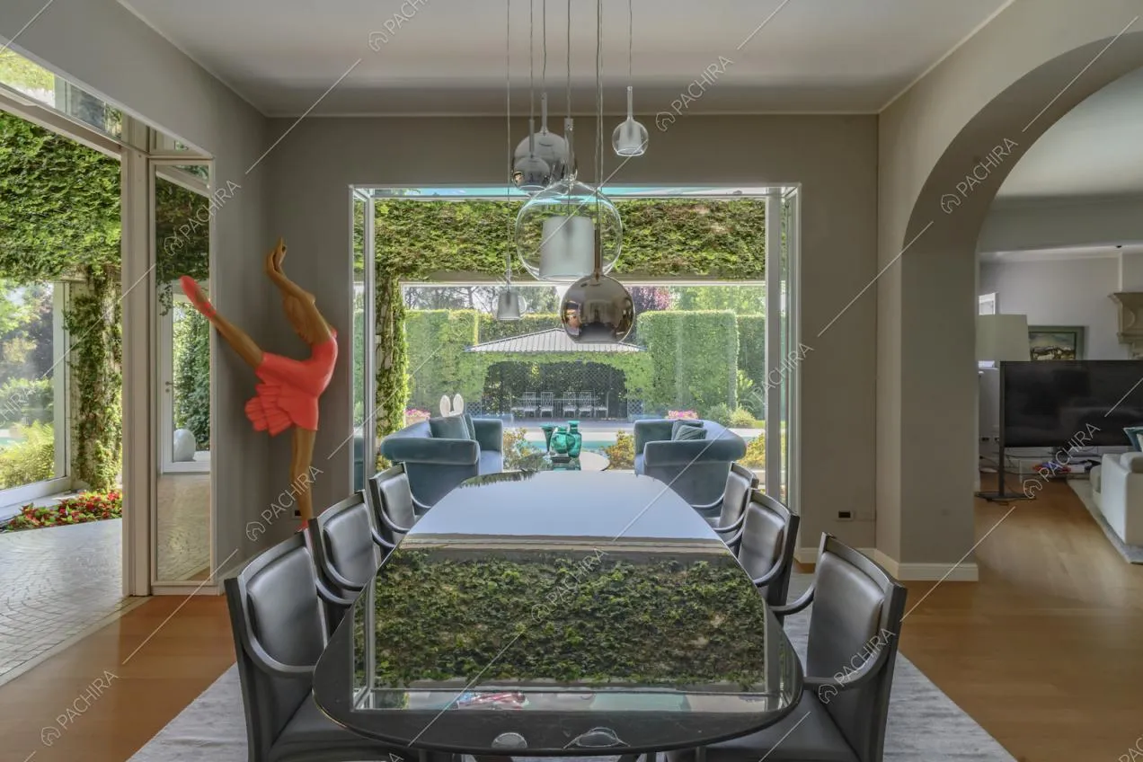 Tavolo da pranzo nella sala con vista sul giardino immerso nel verde tramite una vetrata