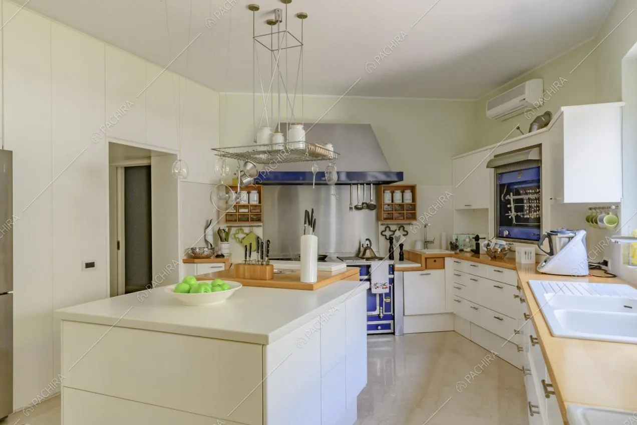 Luminosa cucina con isola bianca, pavimento in marmo e pareti verde chiaro