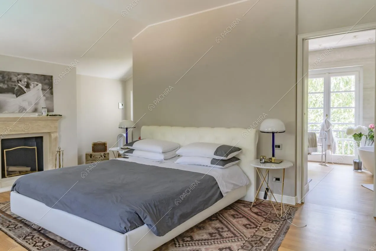 Camera da letto matrimoniale con camino, parete divisoria grigia e pavimento in parquet