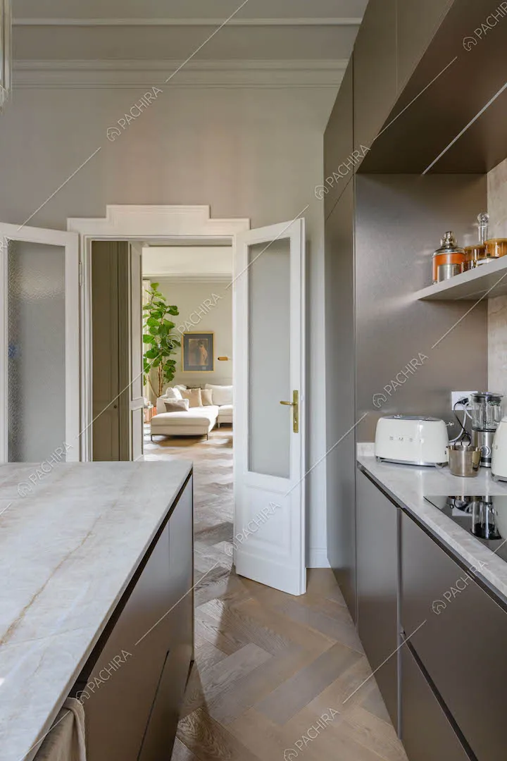 Isola in marmo e fornelli a induzione nella cucina con pavimento in parquet e vista sulla sala