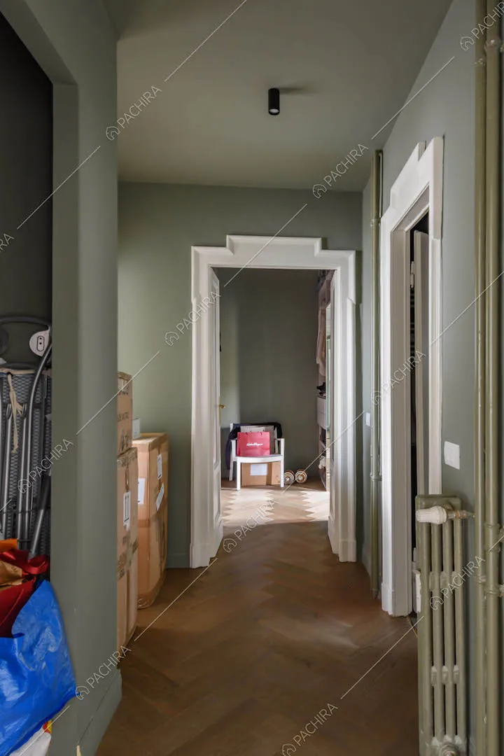 Corridoio con pareti verdi, cornice delle porte con boiserie e pavimento in parquet a spina di pesce