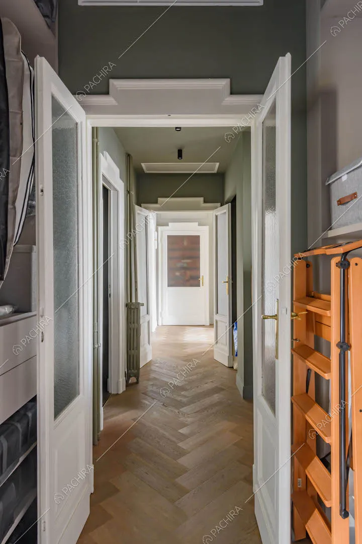 Lungo corridoio con porta a vetri e pavimento in parquet a spina di pesce