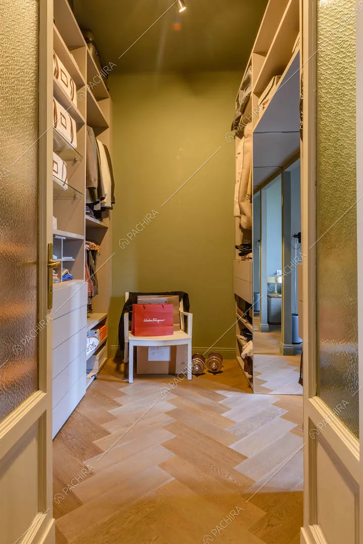 Corridoio con porta a vetri, parete verde e pavimento in parquet a spina di pesce