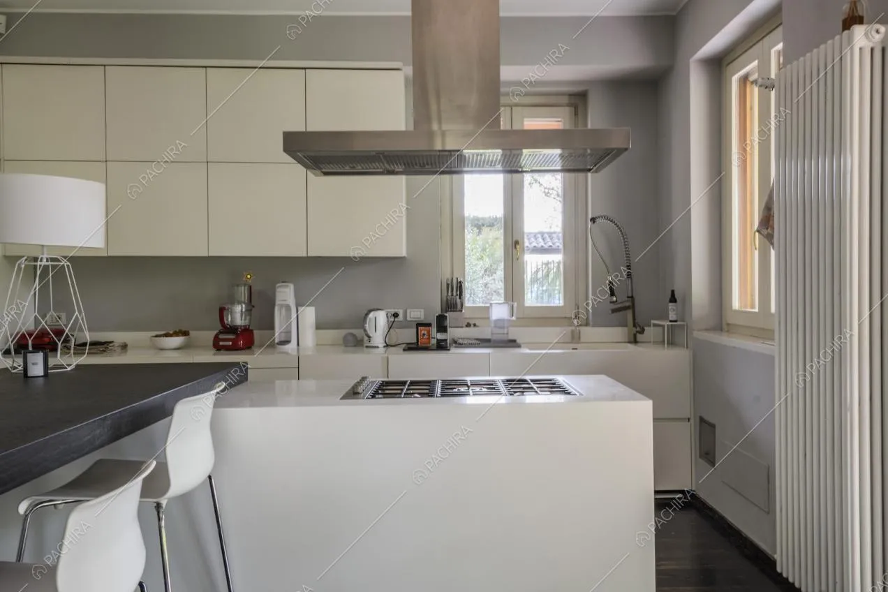 Cucina a isola con mobili bianchi e fornelli a gas
