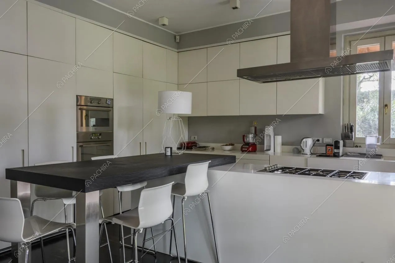 Cucina a vista con elettrodomestici e tavolo con sgabelli