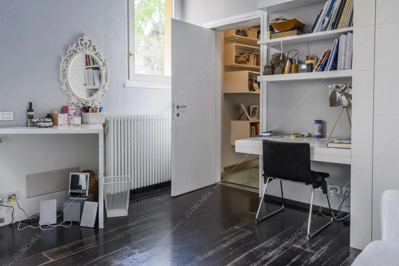 Scrivania con mensole, sedia e specchio ovale appeso alla parete
