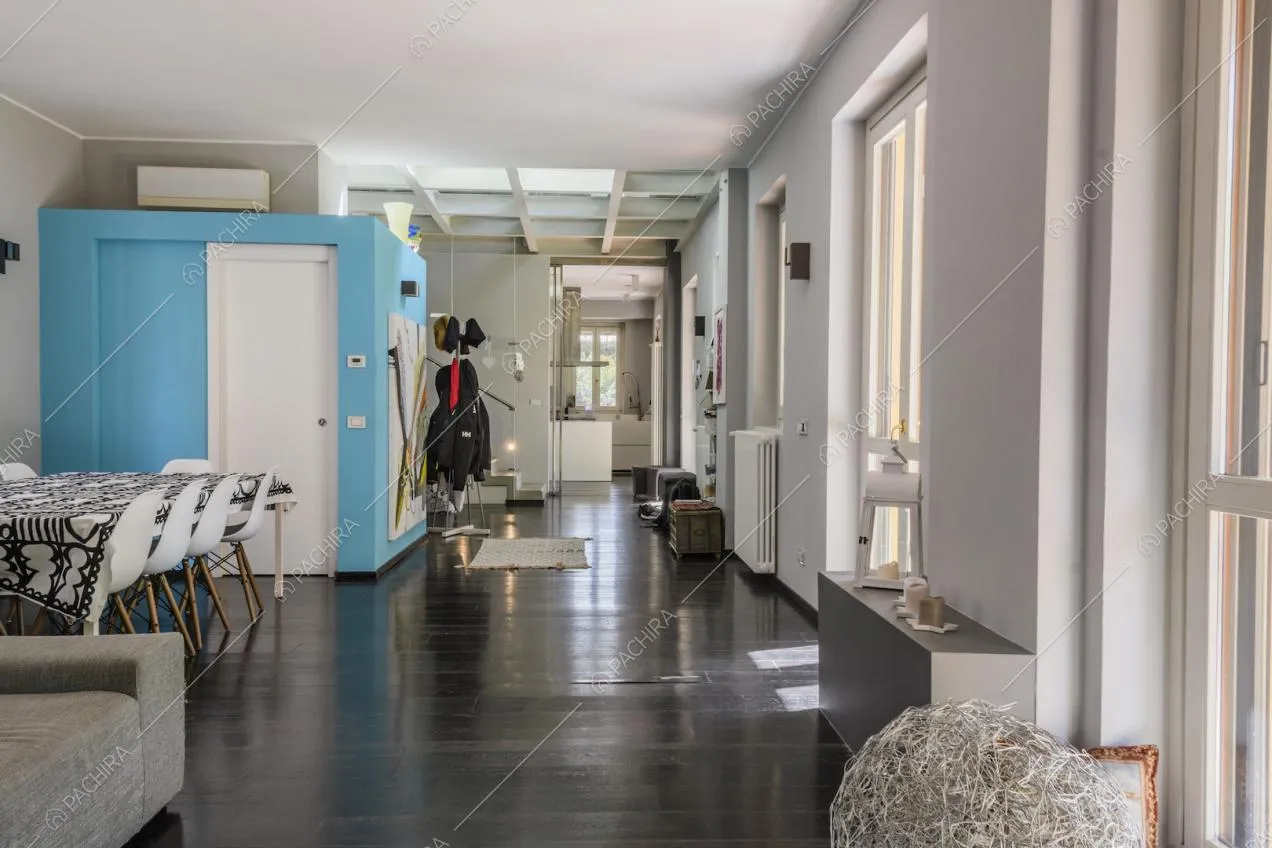 Pavimento in parquet scuro, finestre e pareti bianche e azzurre all'interno della zona giorno