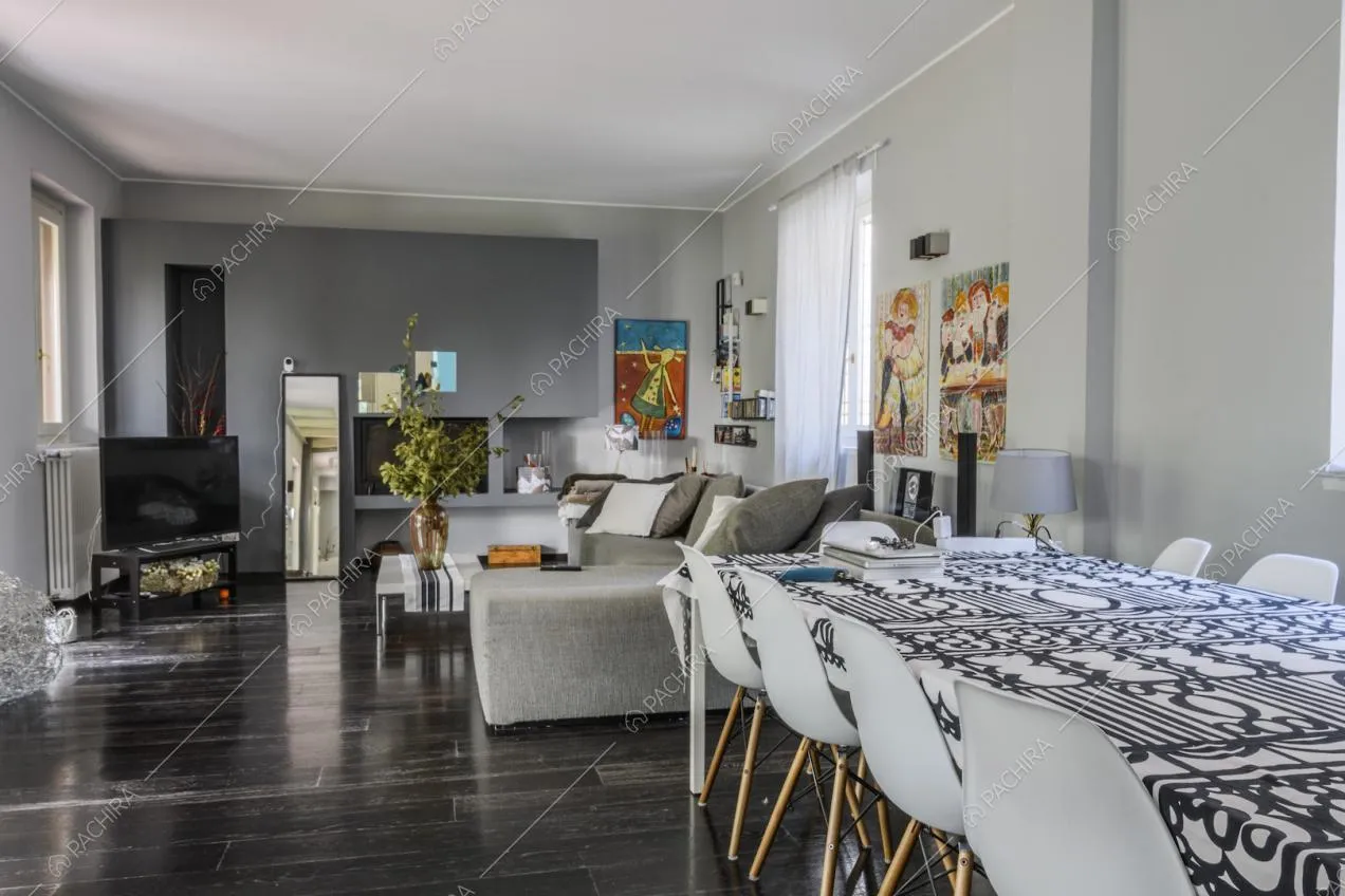 Tavolo da pranzo con sedie bianche di design, pareti grigie e parquet nero
