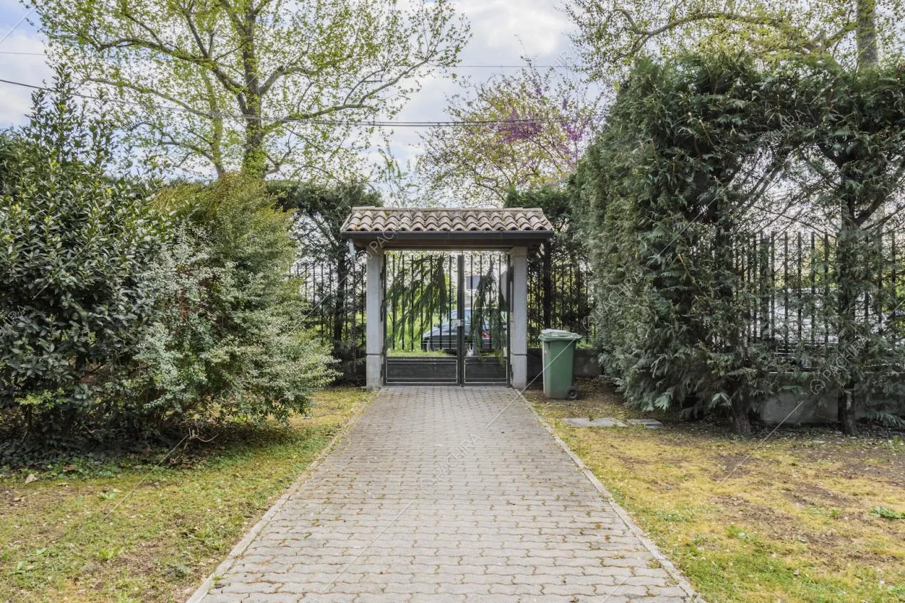 Vialetto in giardino con pietre regolari e cancello d'ingresso con tettoia