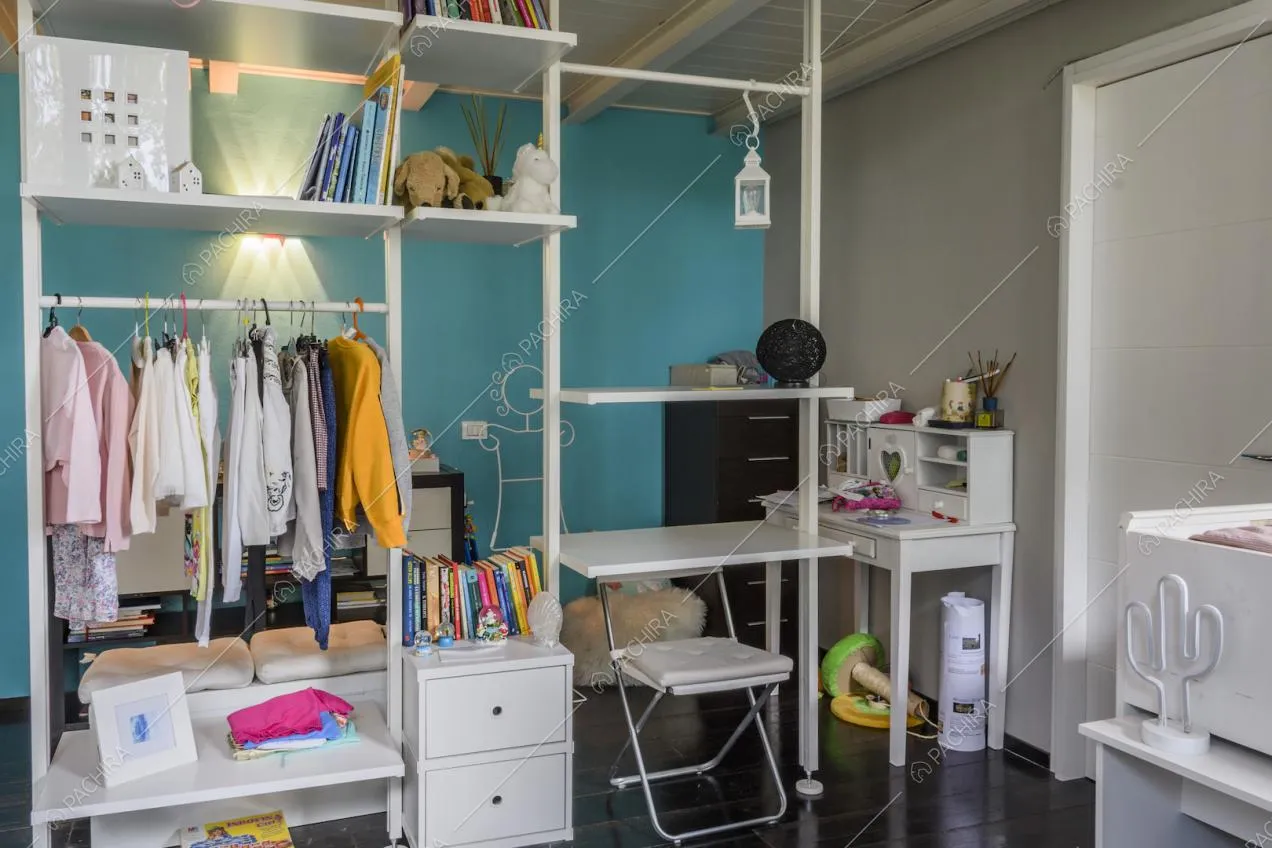 Mobile bianco con vestiti e parete azzurra