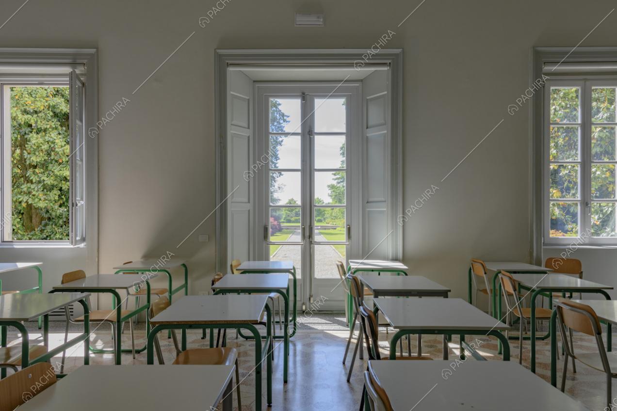 Aula scolastica con banchi bianchi e vista sul parco