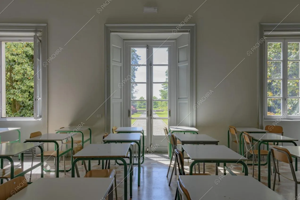 Aula scolastica con banchi bianchi e vista sul parco