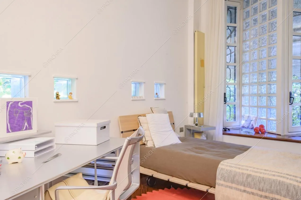 Letto singolo, scrivania con sedie e parete in vetrocemento