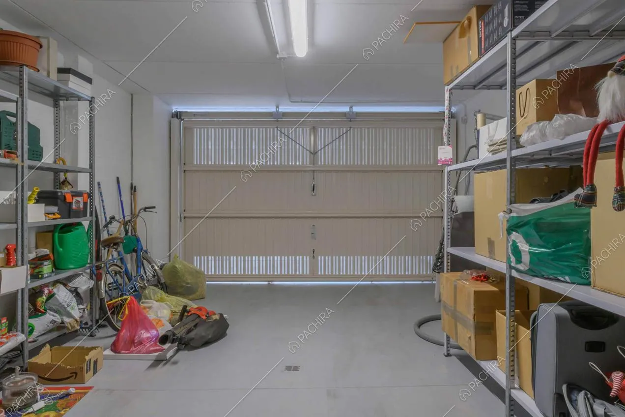 Garage con porta bianca e pavimento in cemento