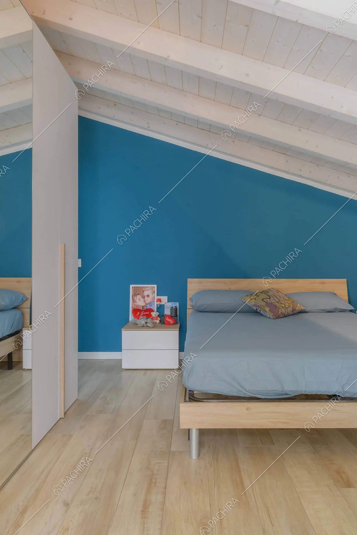 Camera da letto matrimoniale con soffitto in travi in legno a vista e parete blu