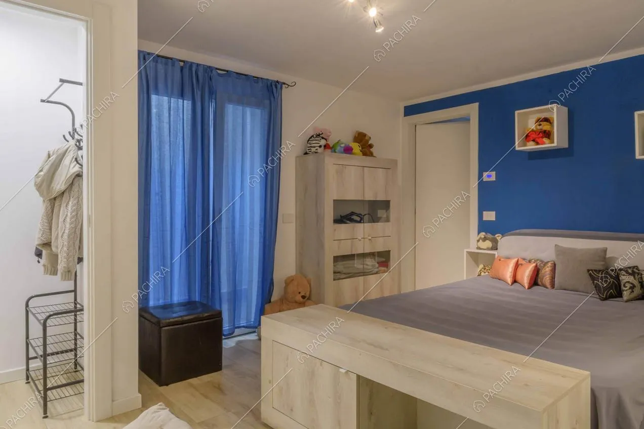 Stanza da letto con parete blu, ingresso nella camera e pavimento in parquet