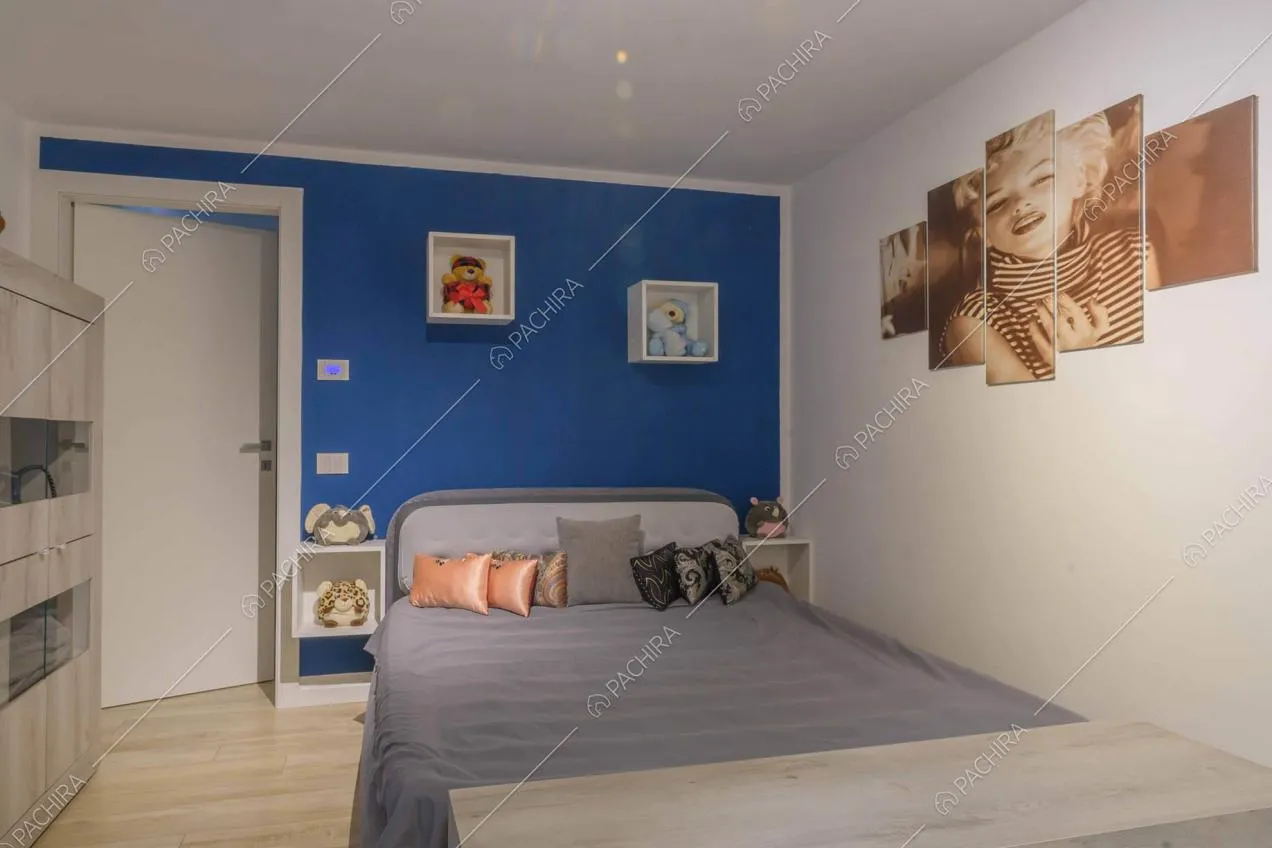 Camera da letto con pavimento in parquet, parete blu e bianca